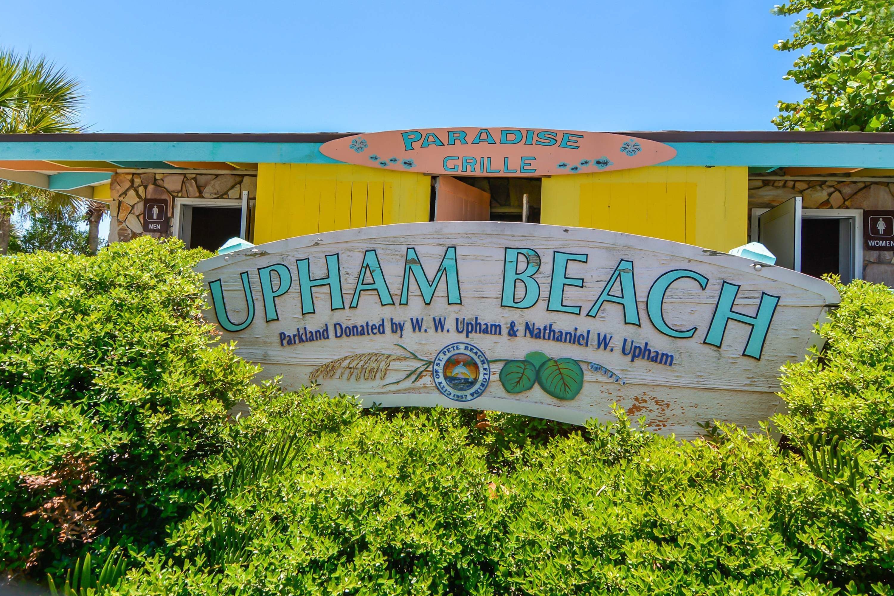 Een bord voor UPHAM BEACH, met een houten bord en een gebouw op de achtergrond.