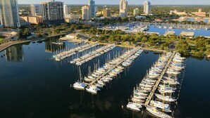 A marina with numerous boats docked, surrounded by high-rise buildings and greenery. - Beachside St Pete Condo w Heated Pool Near Landmark Restaurants (St. Pete Beach)