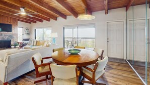 A spacious living area with a wooden ceiling, a round wooden table with chairs, a sofa, and a television. - 3rd floor beachfront condo with beach access pool Gulf views WD balcony AC (Treasure Island)