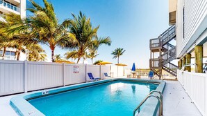 A swimming pool with a 6 ft depth marker, surrounded by palm trees and a white fence. - 3rd floor beachfront condo with beach access pool Gulf views WD balcony AC (Treasure Island)