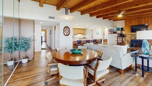 A spacious living area with a wooden ceiling, a round dining table with chairs, a sofa, and a television. - 3rd floor beachfront condo with beach access pool Gulf views WD balcony AC (Treasure Island)