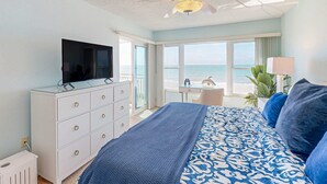A bedroom with a bed, a TV on a dresser, a desk, and a view of the ocean. - Chic and comfortable Gulf front condo snowbird and dog friendly pool beaches (Belleair Beach)