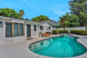 A modern house with a swimming pool, a hot tub, and a patio with lounge chairs. - Large heated pool home with backyard oasis, AC and Wifi (Seminole)