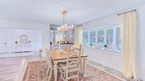 A dining area with a wooden table and chairs, a patterned rug, and a chandelier. - Large heated pool home with backyard oasis, AC and Wifi (Seminole)
