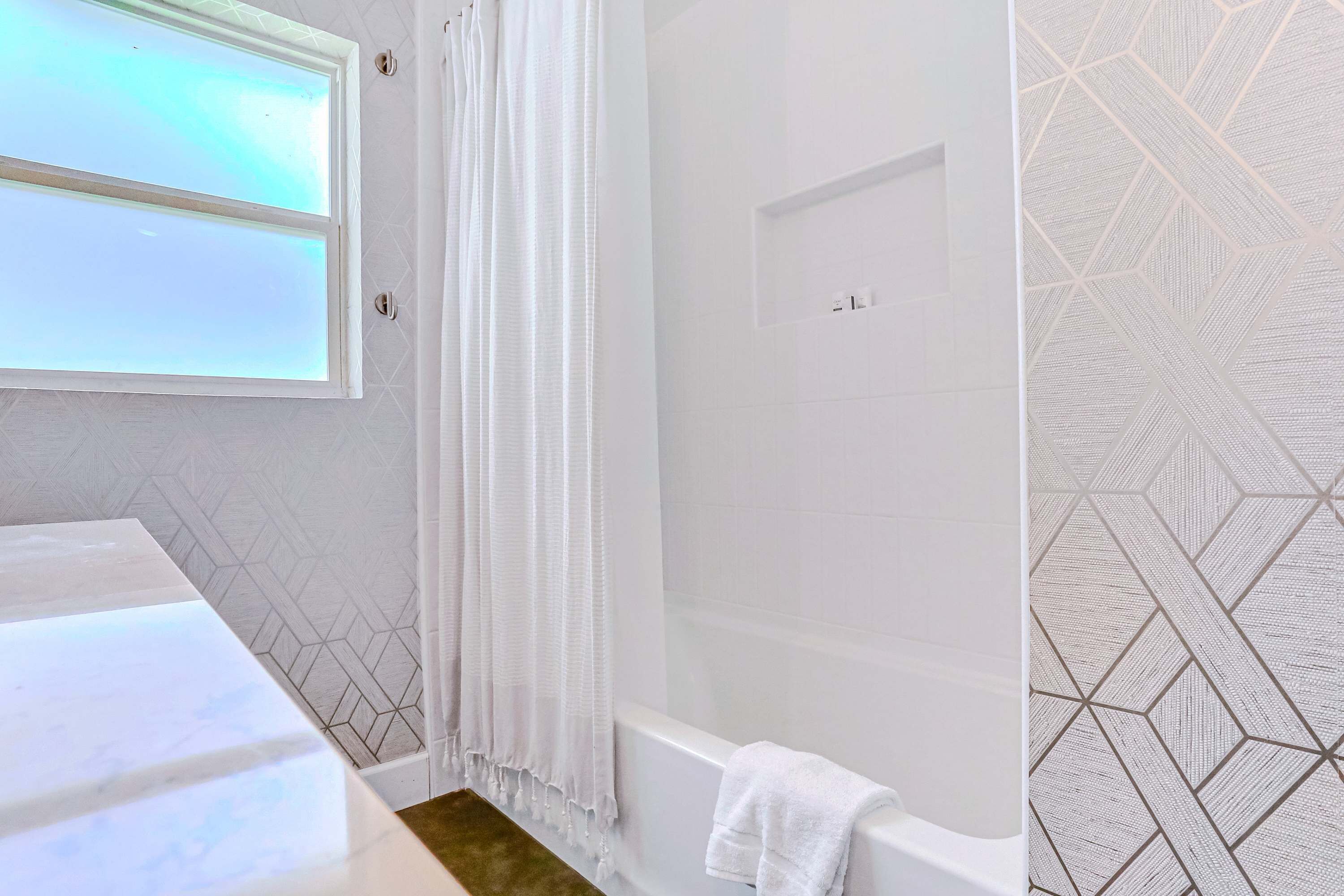 A modern bathroom with a large mirror, a bathtub, and a shower area.