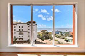 Ampia finestra con vista su una zona costiera, che include edifici e una spiaggia.