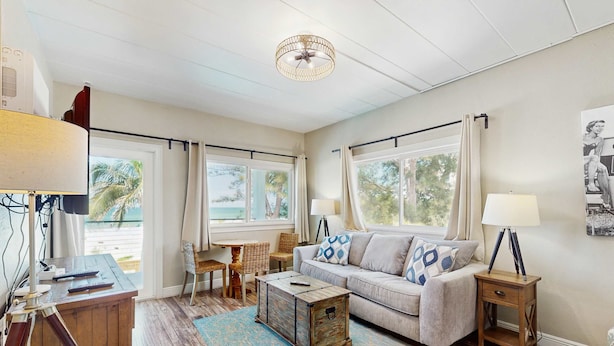 A living room with a sofa, coffee table, and side table, a wooden chest, and a lamp.