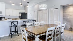 Una cocina moderna con armarios blancos, una mesa de comedor de madera y taburetes negros.