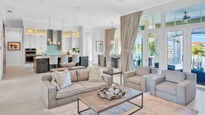 A modern living room with a sofa set, a coffee table, and a dining area with a kitchen in the background.