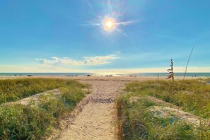 A sandy beach path leading to the ocean with a clear sky and sun. - Second floor condo with beach access balcony pool hot tubs and ping pong (Treasure Island)