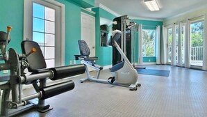 Un gimnasio con equipo de ejercicio, un espejo y ventanas amplias.