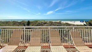 Ein Balkon mit Holzliegen mit Blick auf einen Strand.