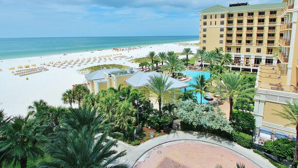 Un resort con playa, piscina y un edificio grande con balcones.
