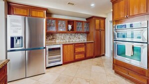 Cocina con armarios de madera, electrodomésticos de acero inoxidable y salpicadero de azulejos.