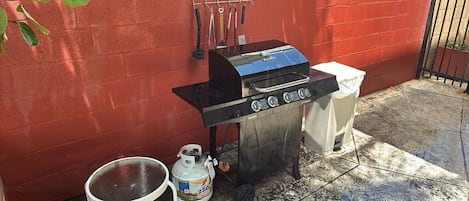 Un barbecue à gaz avec une bouteille de gaz et une table à proximité.