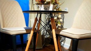 Una habitación con dos sillas, una mesa con un centro de mesa floral y un manto de piel en el suelo.