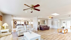 A spacious living room with a ceiling fan, a white coffee table, a beige sofa, and a brown leather couch. - Riverfront home near downtown Tampa with panoramic river views streaming WD (Tampa)