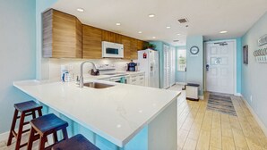 Een moderne keuken met een groot eiland, inbouwapparatuur en een lichtblauw kleurenpalet.