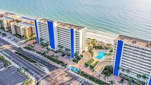 Ein Hochhaus-Hotel mit mehreren Stockwerken, einem Pool und Blick auf den Strand.