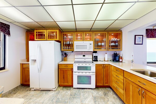 A kitchen with wooden cabinets, a white refrigerator, a microwave, and a double oven.