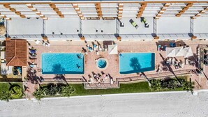 Vista aérea de un hotel con dos piscinas, una zona de estar cubierta y una playa.
