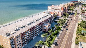 Un hotel junto a la costa con varios pisos, vistas a la playa y un estacionamiento.