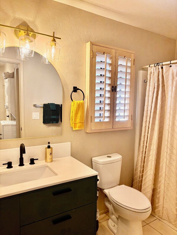 A bathroom with a white sink, black faucet, and a mirror above it. There is a toilet with a beige seat and a shower curtain with a diamond pattern. - Golf & Ski Get-away Pinetop (Pinetop-Lakeside)