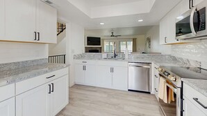 A modern kitchen with white cabinets, a stainless steel dishwasher, a built-in oven, and a microwave. - Spacious and dog friendly close to the Gulf and beaches AC WIFI and WD (Treasure Island)