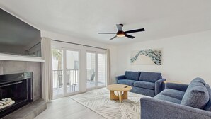 A modern living room with a fireplace, a ceiling fan, a blue sofa, and a patterned rug. - Spacious and dog friendly close to the Gulf and beaches AC WIFI and WD (Treasure Island)