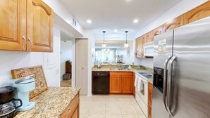 A modern kitchen with wooden cabinets, stainless steel appliances, and a granite countertop. - Coastal condo with beach and pool access balcony WD central air and water views (Indian Shores)