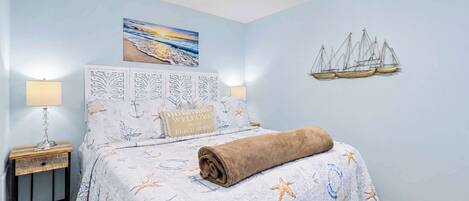 A bedroom with a bed, nightstands, a ceiling fan, a painting, and wall decor.
