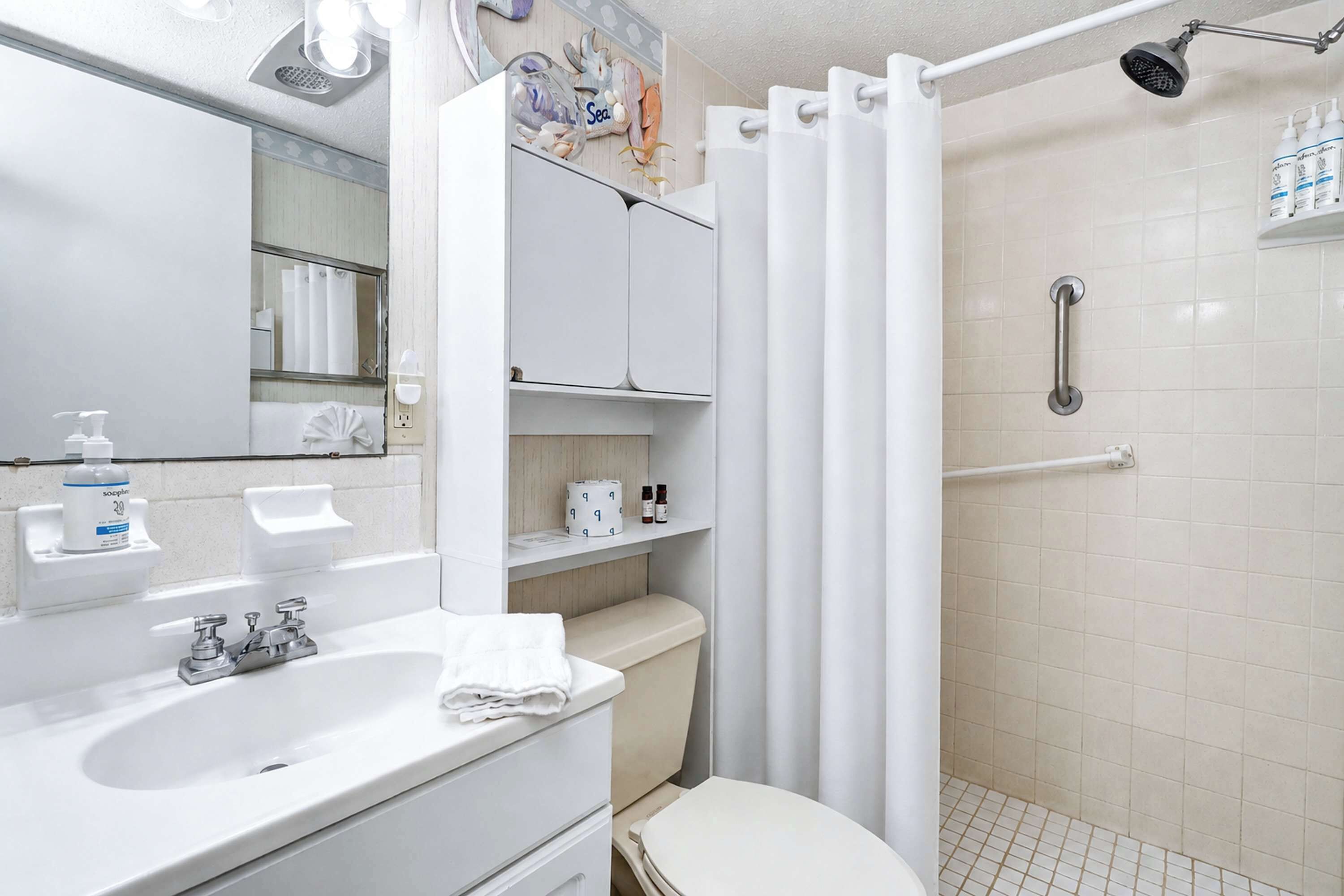 Un baño con ducha, inodoro, lavamanos y espejo.