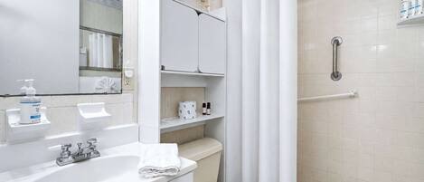 Un baño con ducha, inodoro, lavamanos y espejo.