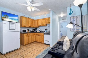 Un espacio habitable compacto con kitchenette, ventilador de techo, televisión de pantalla plana y sofá.