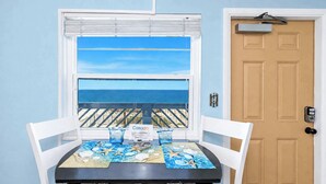 A room with a table set for two, a window with a view of the ocean, and a door with a mailbox.