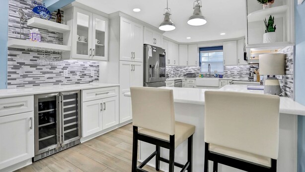 A modern kitchen with white cabinets, a built-in oven, and a central island with bar stools. - Stunning centrally located home with enclosed yard patio grill WD and AC (Largo)