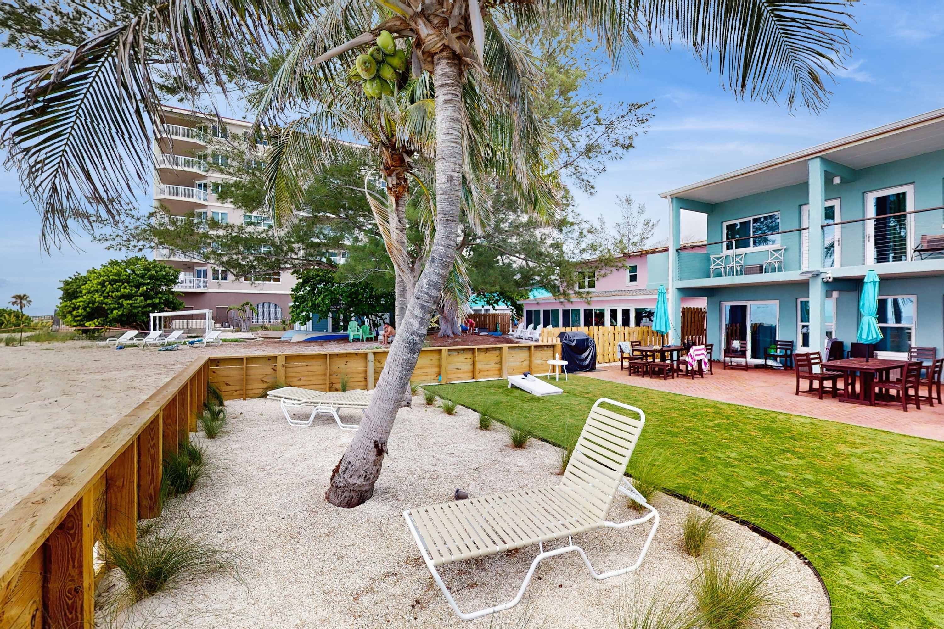 A beachfront property with a pool, lounge chairs, and a building with a balcony.