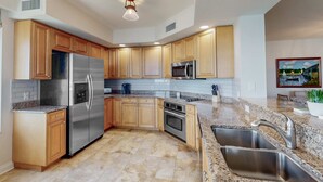 A modern kitchen with wooden cabinets, stainless steel appliances, granite countertops, and a built-in oven. - Luxury stunning waterfront condo Central AC pool snowbird friendly (Clearwater)