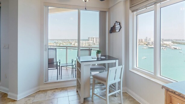 A balcony with a dining table and chairs, a potted plant, and a view of the marina. - Luxury stunning waterfront condo Central AC pool snowbird friendly (Clearwater)
