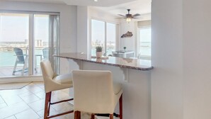 A modern kitchen with a bar area, large windows, and a view of the city. - Luxury stunning waterfront condo Central AC pool snowbird friendly (Clearwater)