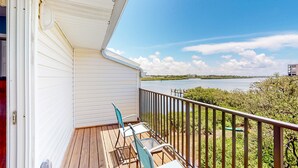 A balcony with a view of a lake, wooden deck, and metal chairs. - Beachfront condo with balconies grill AC and pool access steps from the sand (Indian Shores)