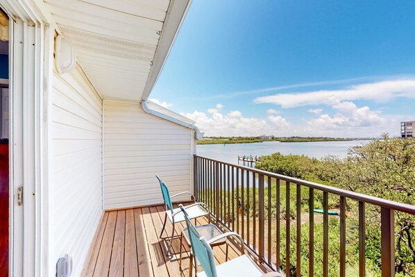 Ein Balkon mit Seeblick, Holzterrasse und Metallstühlen.