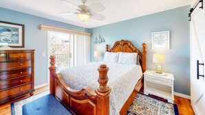 A bedroom with a wooden bed, a ceiling fan, a nightstand, and a window with blinds. - Beachfront condo with balconies grill AC and pool access steps from the sand (Indian Shores)