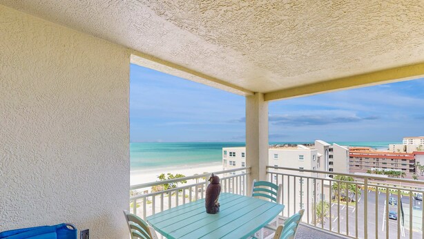 Ein Balkon mit Tisch und Stühlen mit Blick auf Strand und Stadtlandschaft.