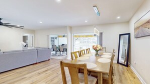 A modern kitchen with a dining area, wooden flooring, and a large window.