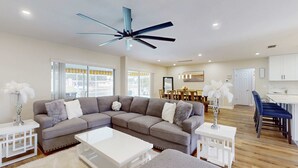 A modern living room with a sectional sofa, a white coffee table, and a ceiling fan.