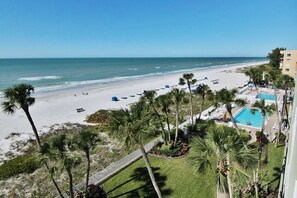 Un complejo turístico en la playa con piscina, palmeras y vistas al océano.