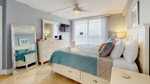 Un dormitorio con cama, cómoda, espejo y vistas al balcón.
