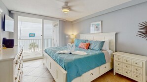 Un dormitorio con cama, mesita de noche, cómoda y balcón con vistas.