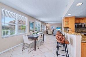 A modern kitchen with a built-in microwave and oven, a dining area with a table and chairs, and large windows with blinds. - Third floor condo with pool access fast WiFi central AC and WD snowbirds OK (Clearwater)